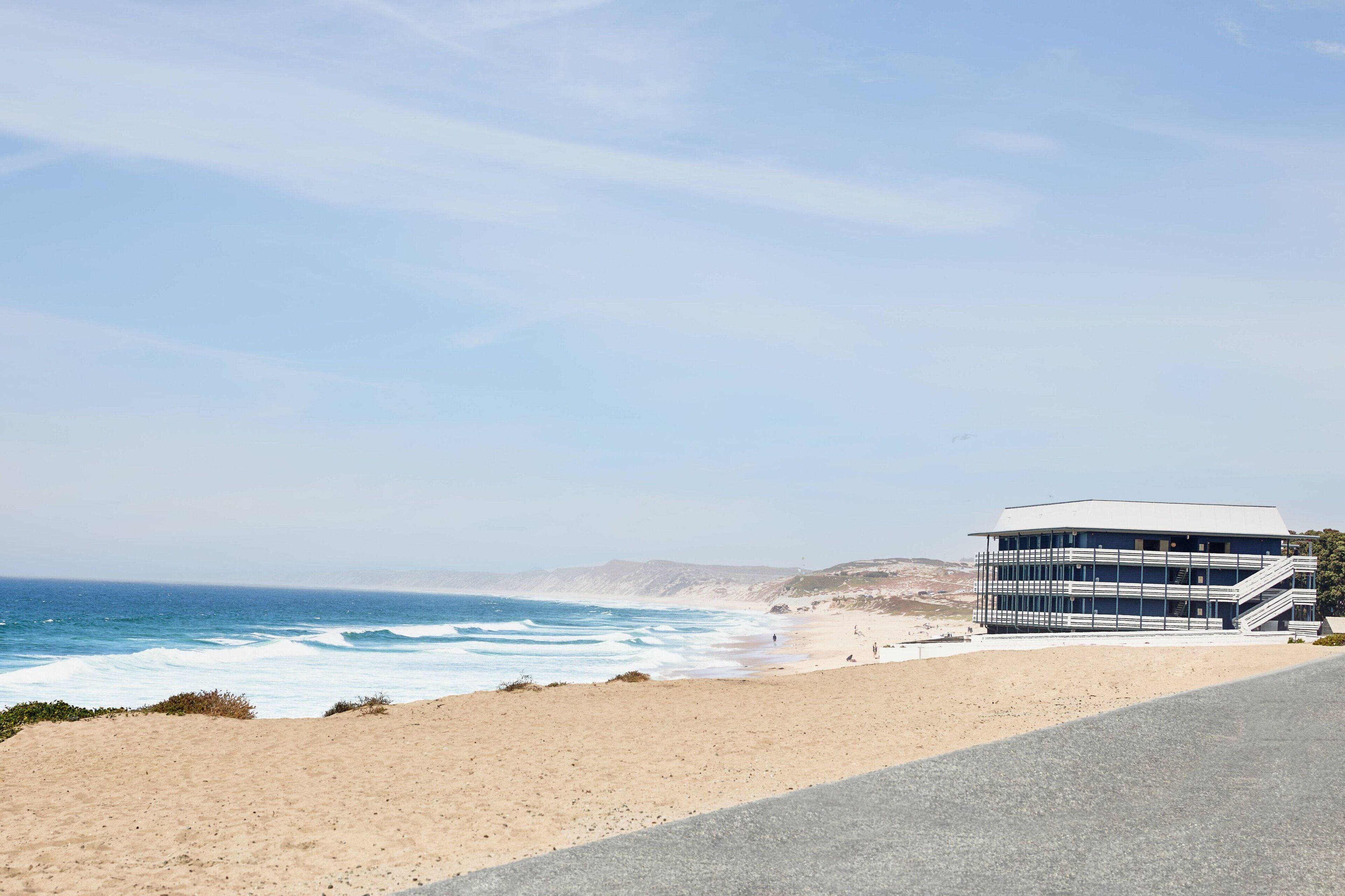 A coastal building with a sandy beach and ocean in the background.