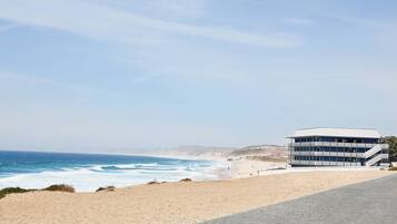 A coastal building with a sandy beach and ocean in the background.