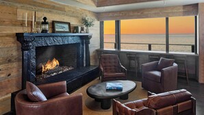 A cozy living room with a fireplace, leather sofas, and a view of the ocean at sunset. - Monterey Beach Hotel, A Tribute Portfolio Hotel (Monterey)