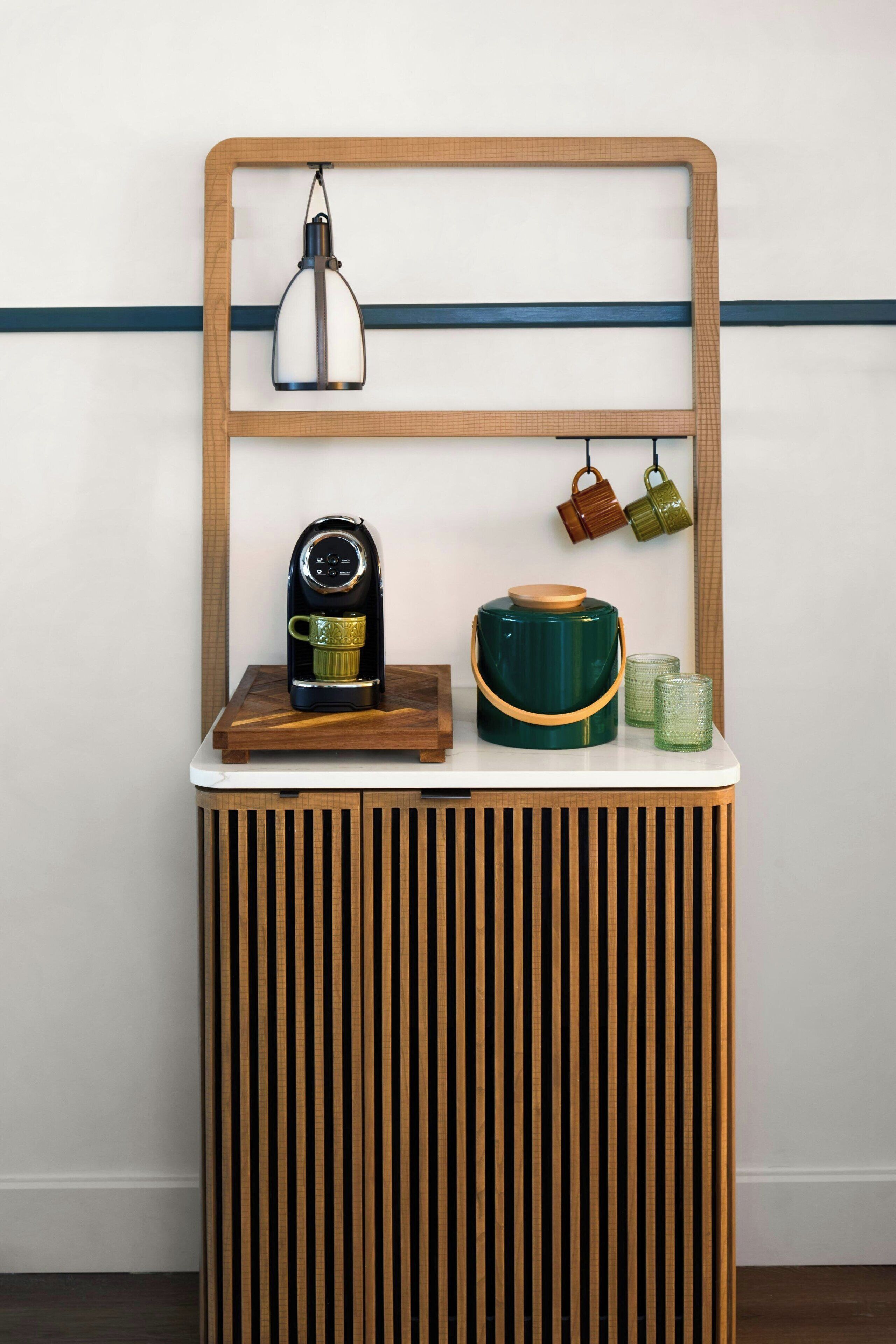 A wooden console table with a coffee maker, a teapot, and two cups.