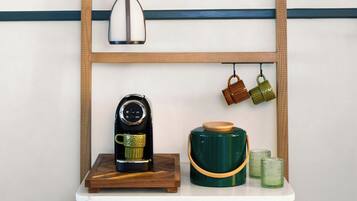 A wooden console table with a coffee maker, a teapot, and two cups.