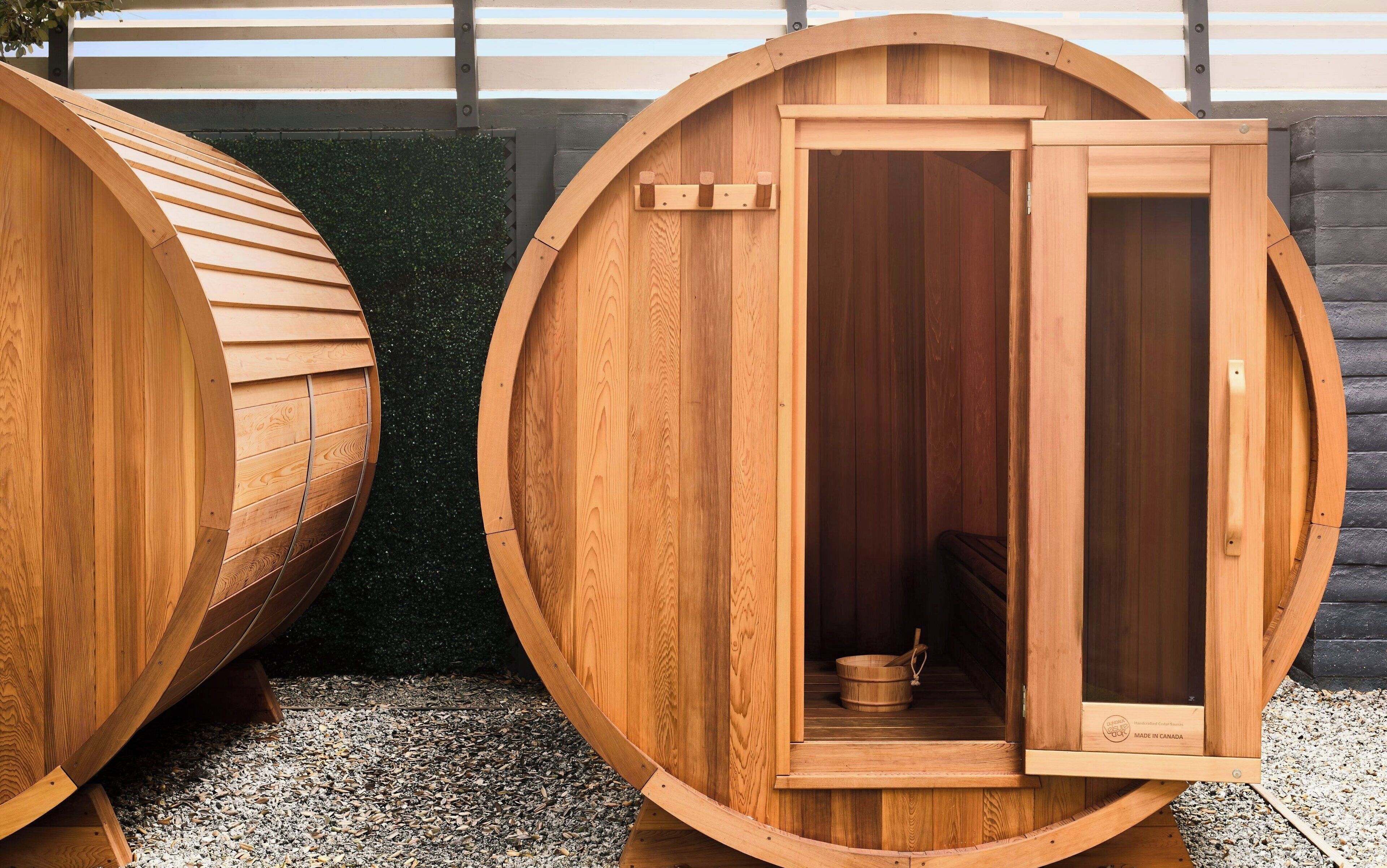 Two wooden saunas with a wooden door and a small wooden bench inside.