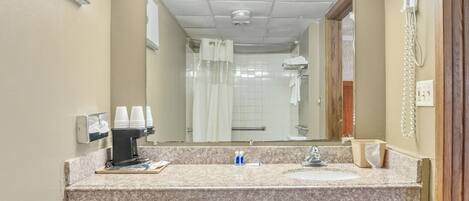 A bathroom with a granite countertop, two sinks, a mirror, a hairdryer, and a towel rack.