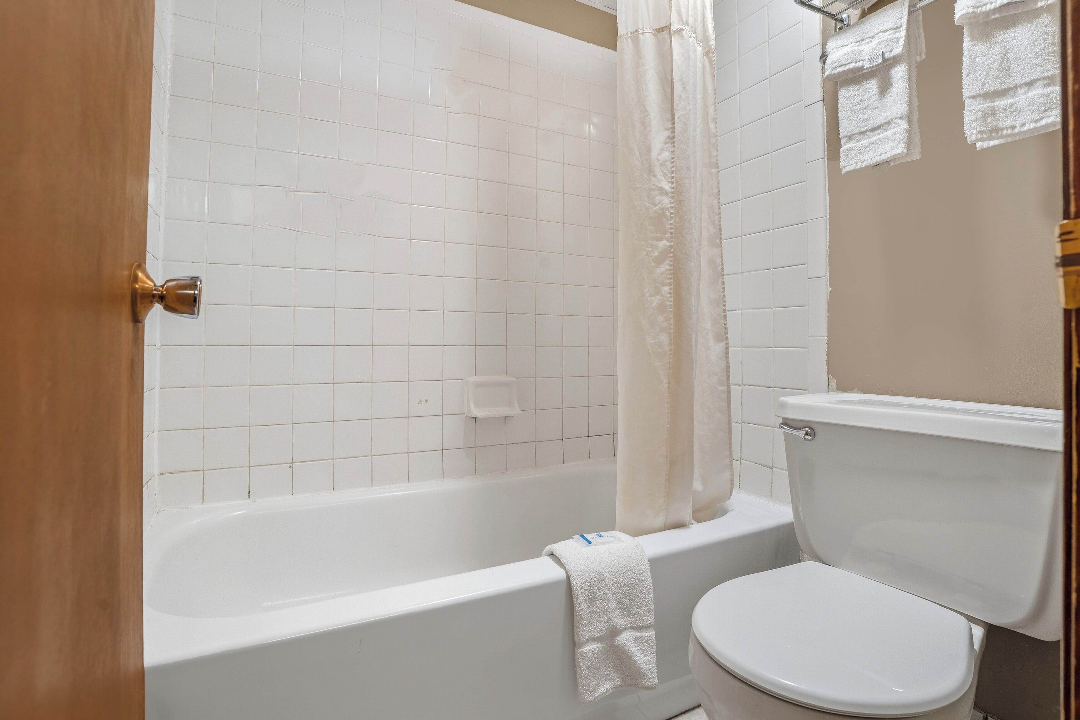 Un baño con una bañera blanca, un inodoro y una cortina de ducha.