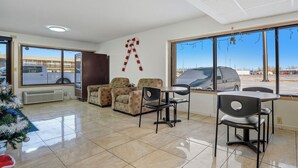 Una habitación de hotel con un ventanal grande, una zona de comedor con una mesa y sillas, un árbol de Navidad y una decoración en la pared.
