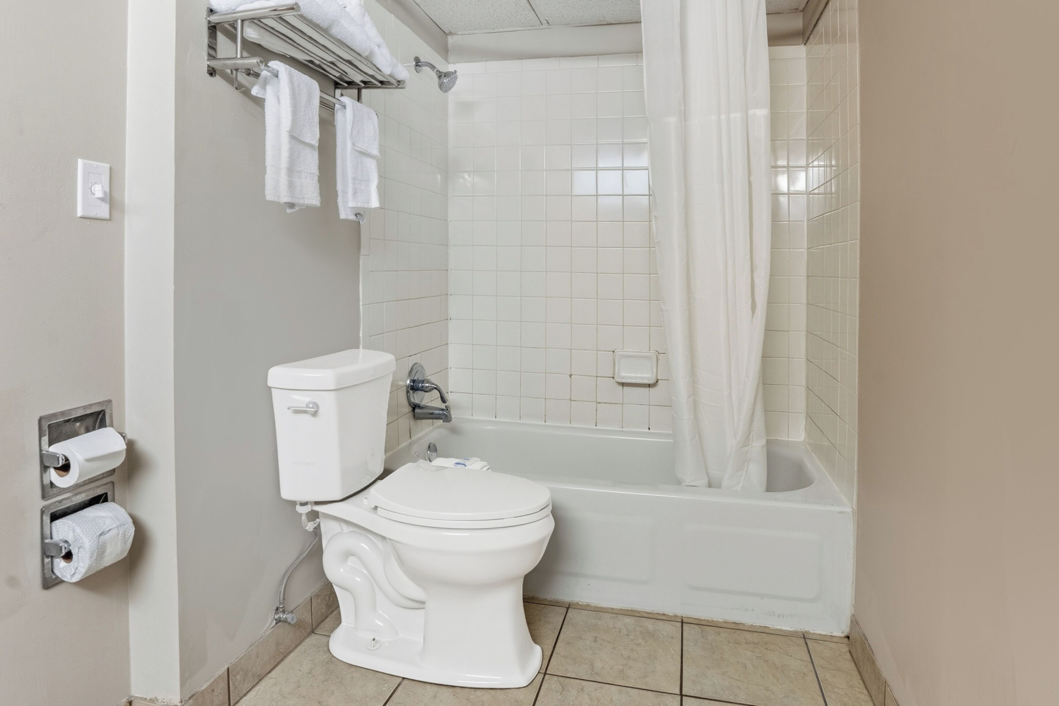 Une salle de bain équipée de toilettes, d’une baignoire et d’un rideau de douche.