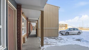 Un pasillo de hotel con paredes de ladrillo, una galería techada y un automóvil estacionado.