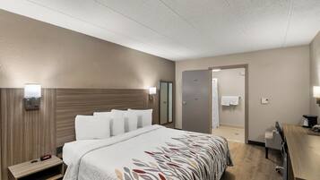 A hotel room with a bed, bedside tables, a desk, and a bathroom door.