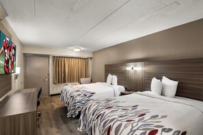 A hotel room with two beds, a desk, a chair, a door, and a window with curtains. - Red Roof Inn Enfield (Enfield)