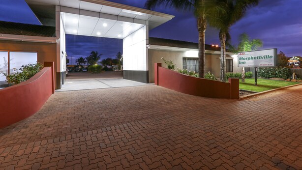 A hotel entrance with a covered walkway, palm trees, and a sign for Morphetville Inn. - Morphettville Motor Inn (Camden Park)