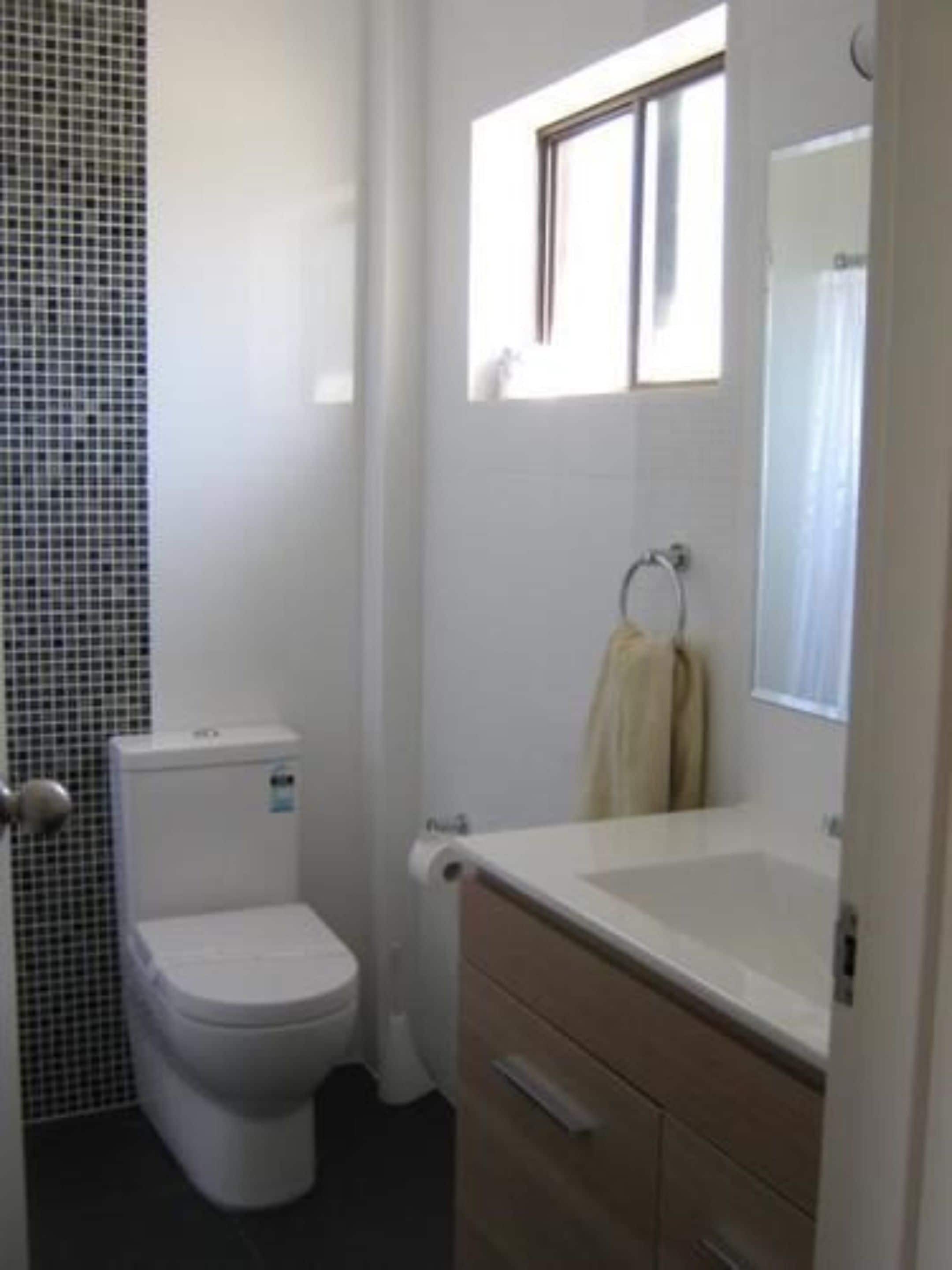 Une salle de bain avec des toilettes, un lavabo et un miroir.