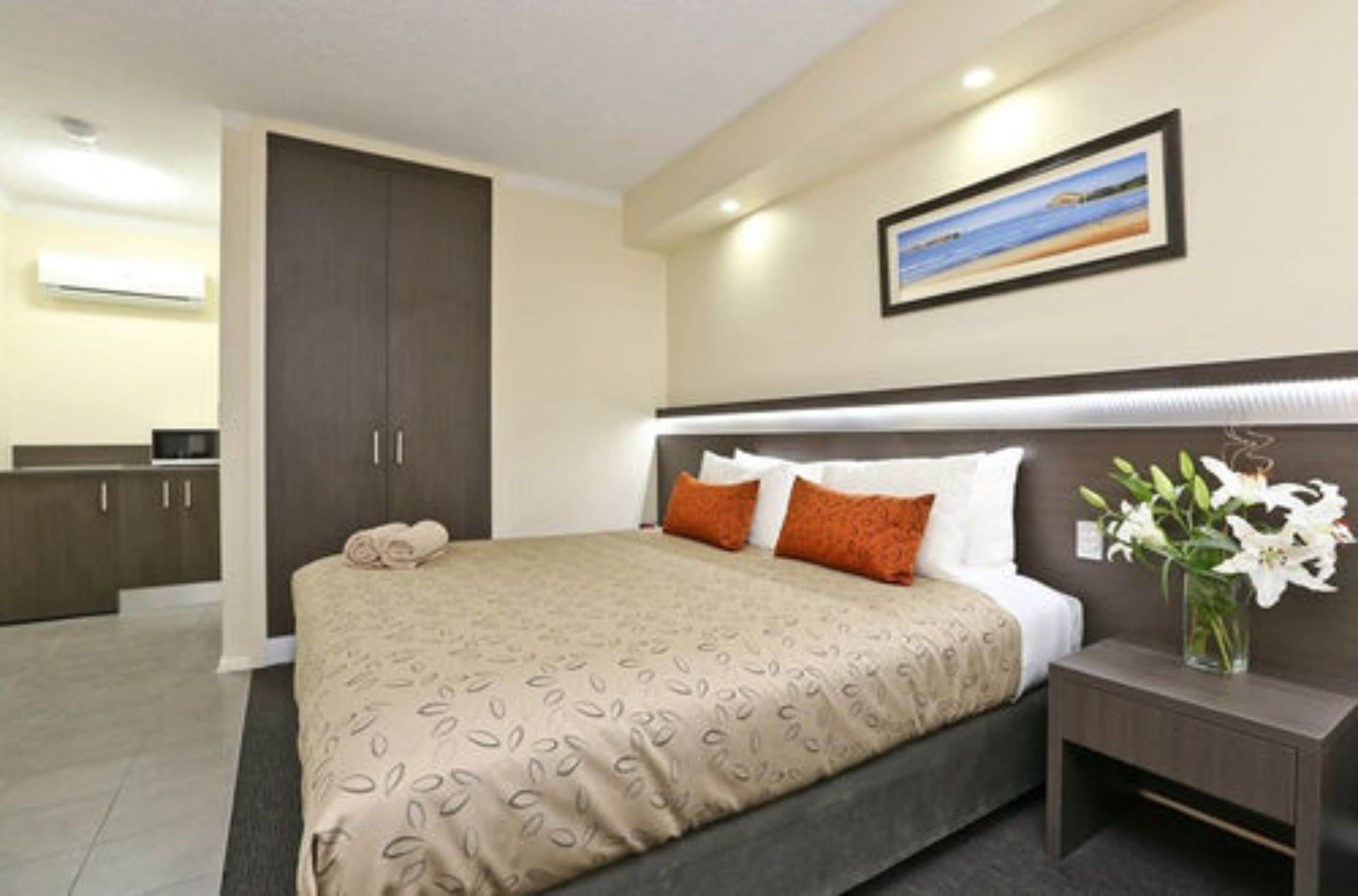 Habitación de hotel con cama, mesita de noche y un cuadro en la pared.
