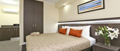 Habitación de hotel con cama, mesita de noche y un cuadro en la pared.