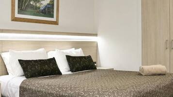 A neatly made bed with patterned bedding, a bedside table, and a wardrobe.
