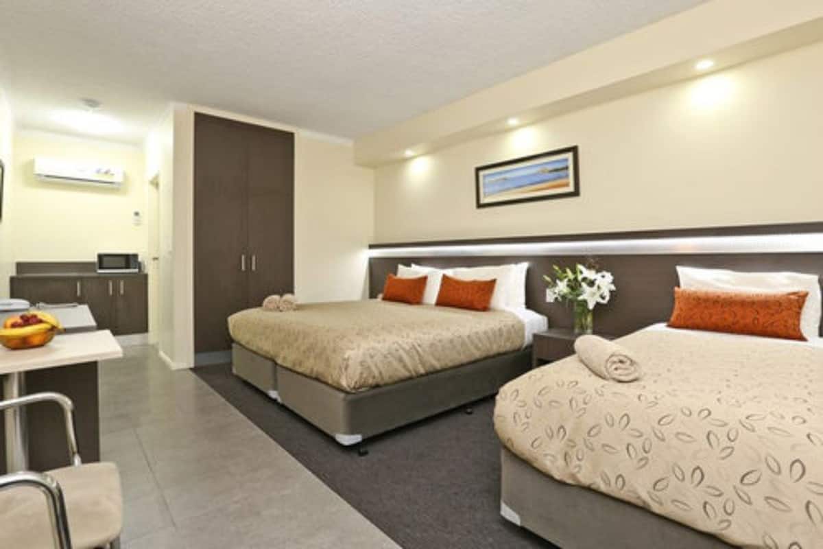 A hotel room with a bed, bedside table, and a small desk with a chair.