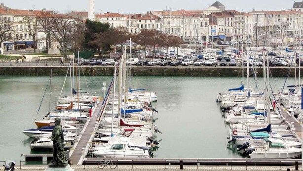 A marina with numerous boats docked, a statue, and a prominent tower in the background. - ibis La Rochelle Centre Historique Hotel (La Rochelle)
