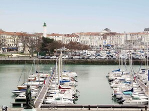A marina with numerous boats docked, a statue, and a prominent tower in the background.