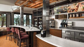 A modern bar area with a curved counter, bar stools, and a coffee machine.
