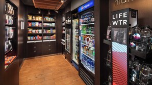 A store with shelves stocked with snacks, a Pepsi refrigerator, and a display of LifeWTR products.