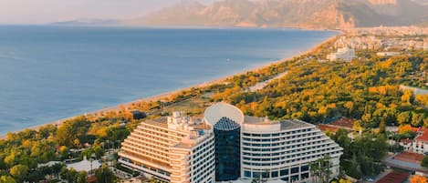 A hotel with multiple floors, a rooftop pool, and a view of the sea.