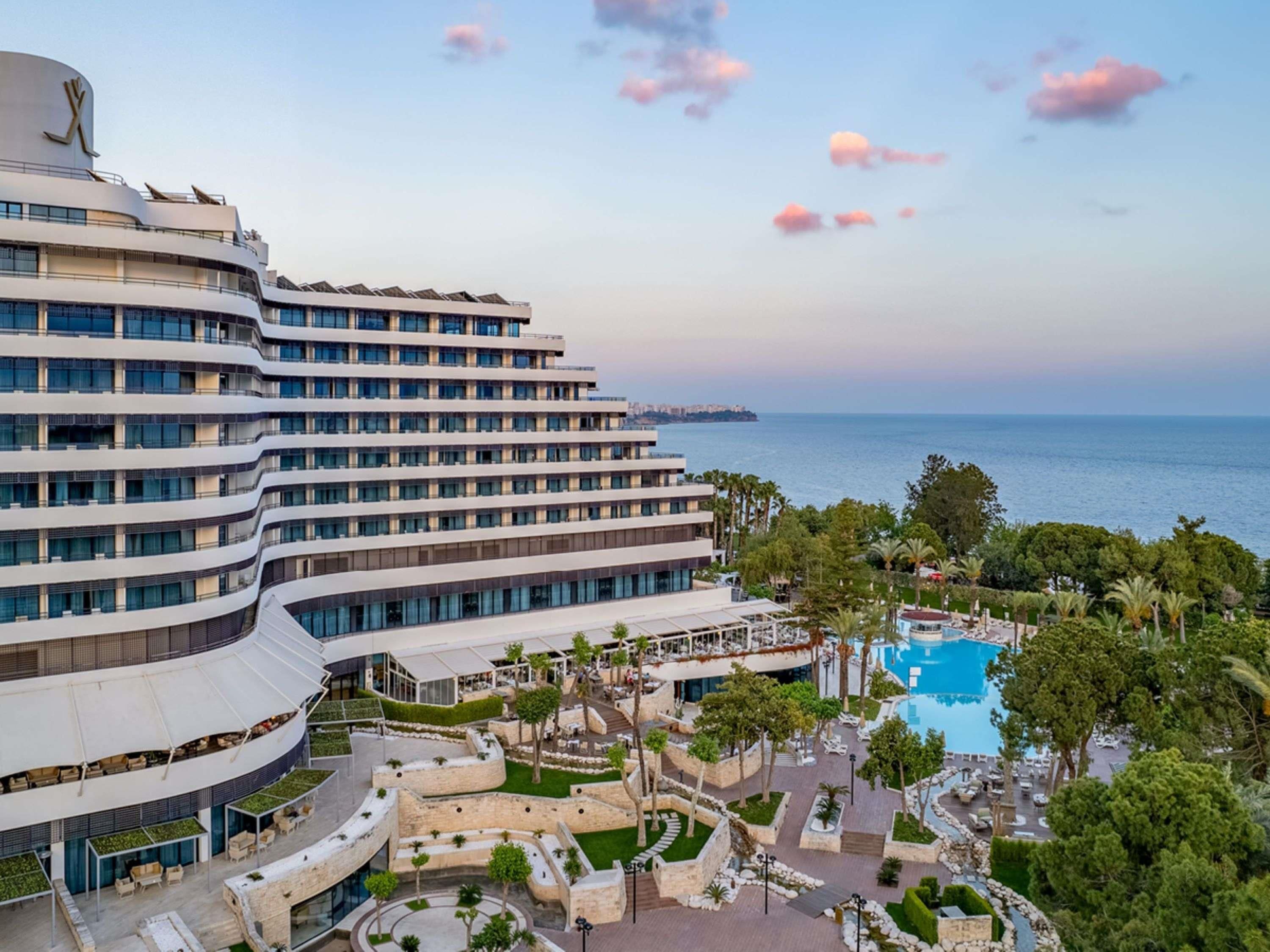 Ein modernes Hotel mit mehreren Etagen, einem Schwimmbad und Meerblick.