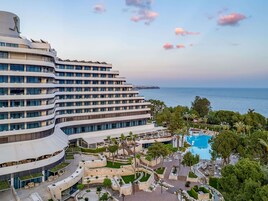 Et moderne hotel med flere etager, en swimmingpool og udsigt til havet.