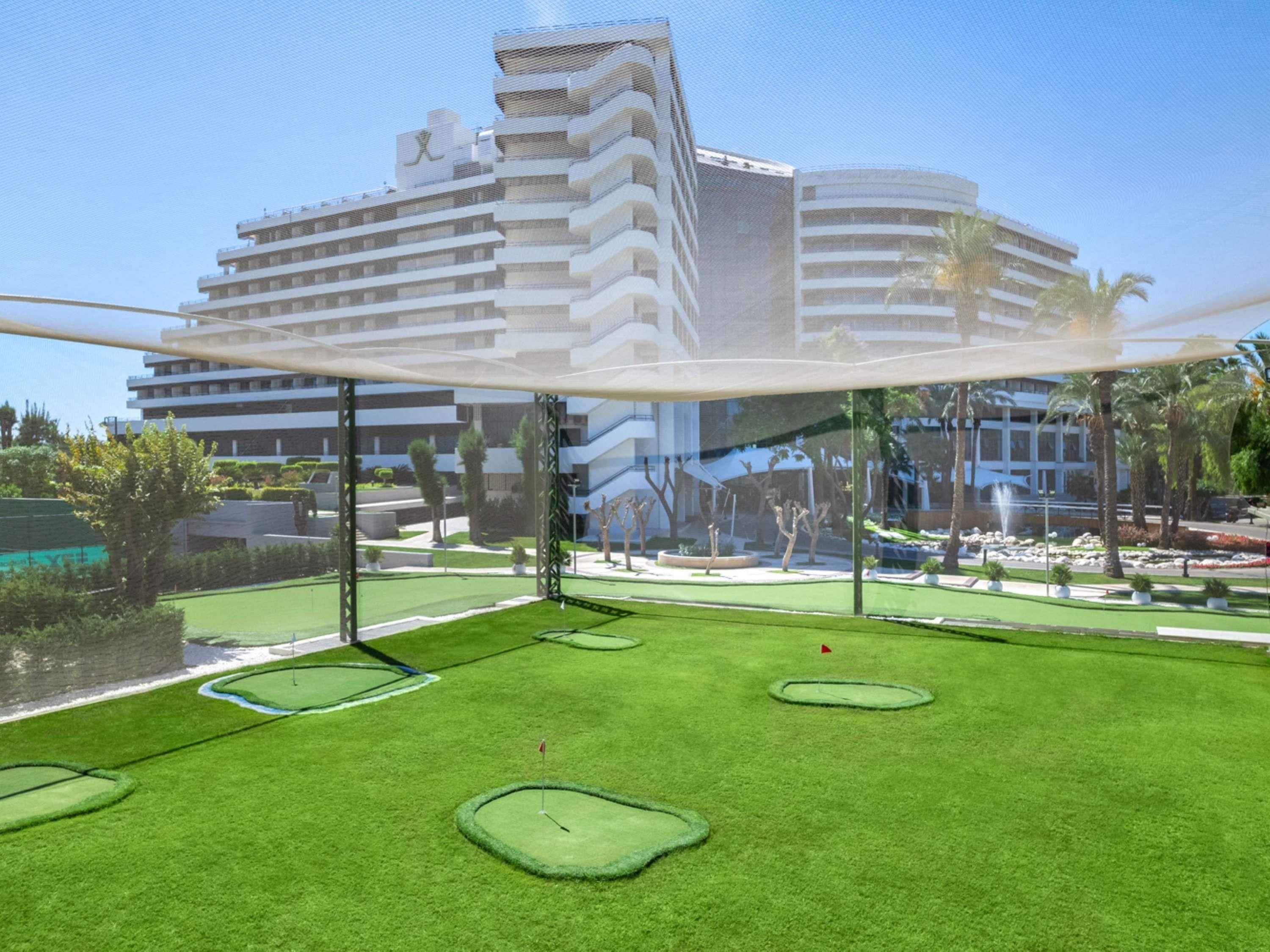 Een golfbaan met een modern gebouw op de achtergrond.