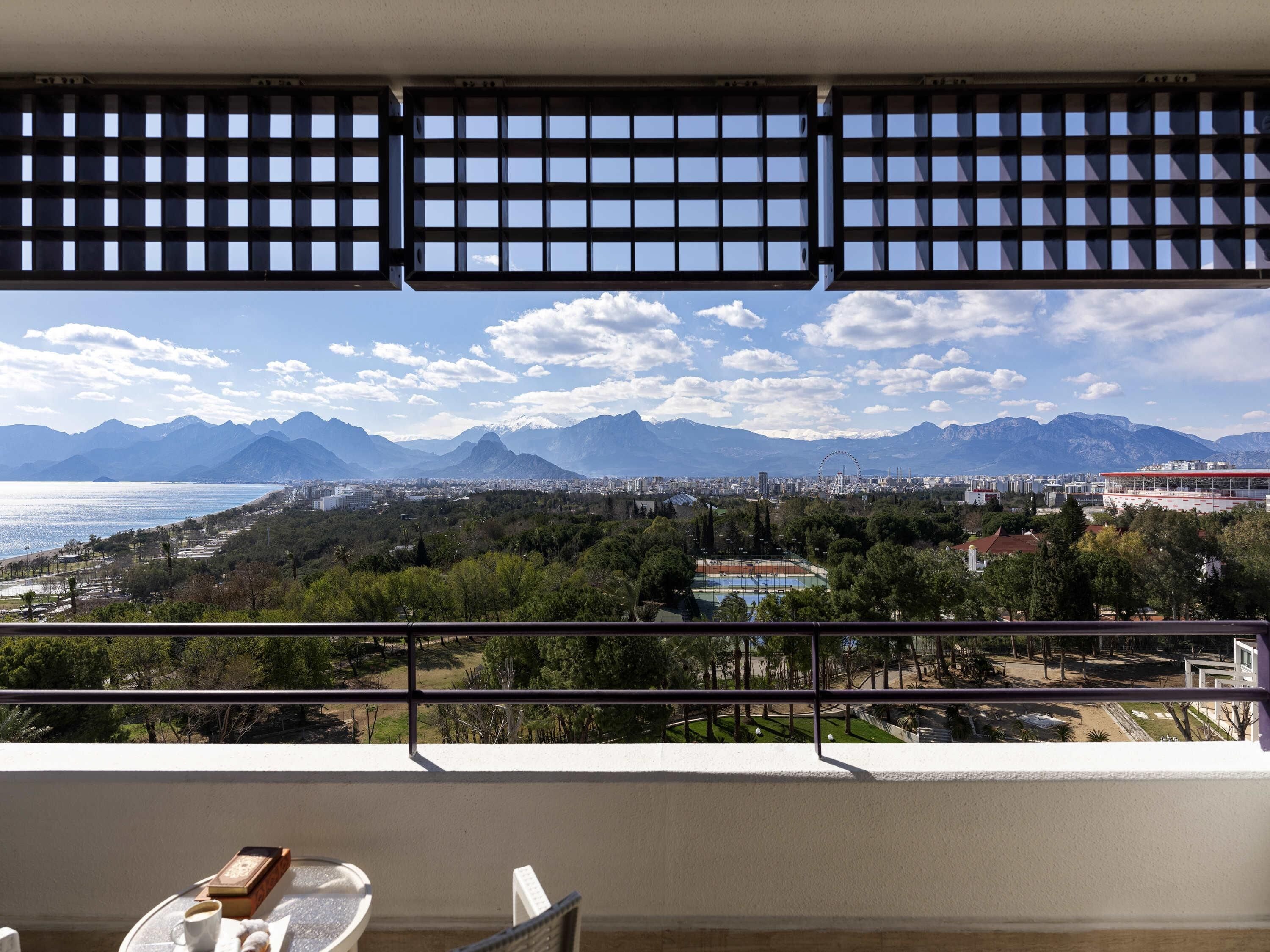 A balcony with a view of a cityscape, mountains, and a body of water.