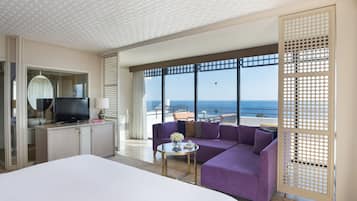 Enjoy the ocean view from the comfort of your room, featuring a large bed, TV, and balcony access.