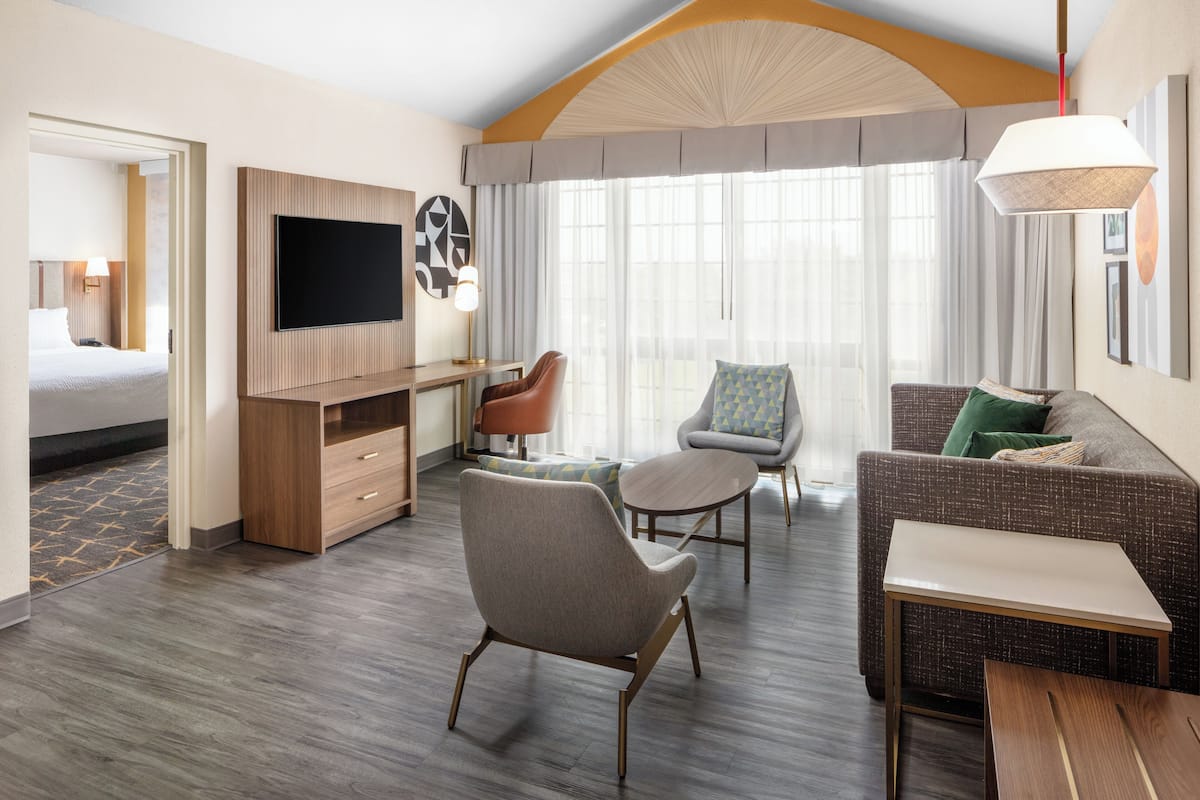 A hotel room with a bed, a desk, a TV, a sofa, and a chair.