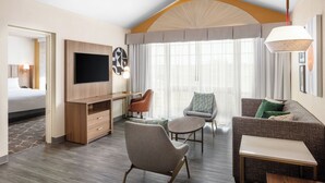 A hotel room with a bed, a desk, a TV, a sofa, and a chair.