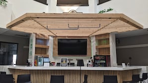A modern bar area with a wooden ceiling, a large flat-screen TV, and a Coca-Cola vending machine.