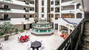 A multi-level atrium with a central water feature, multiple balconies, and indoor seating areas.