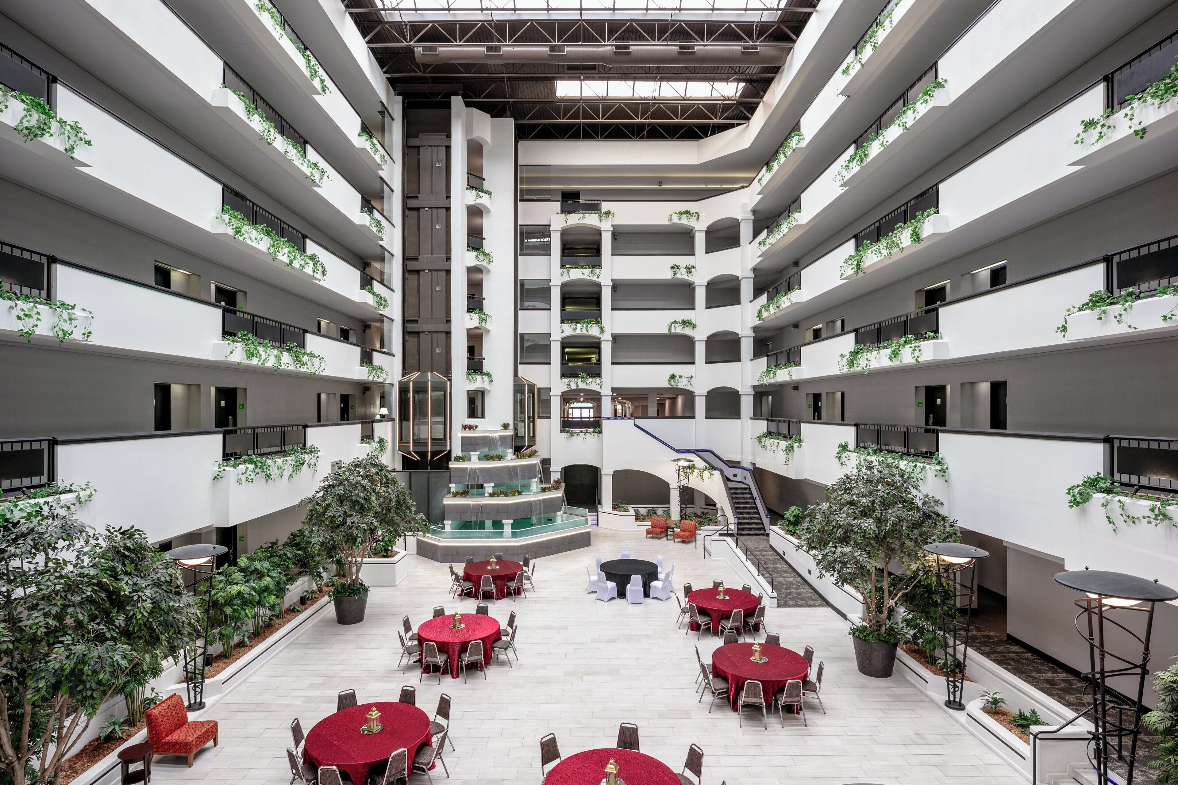 A multi-level atrium with multiple dining areas, indoor plants, and a central staircase.