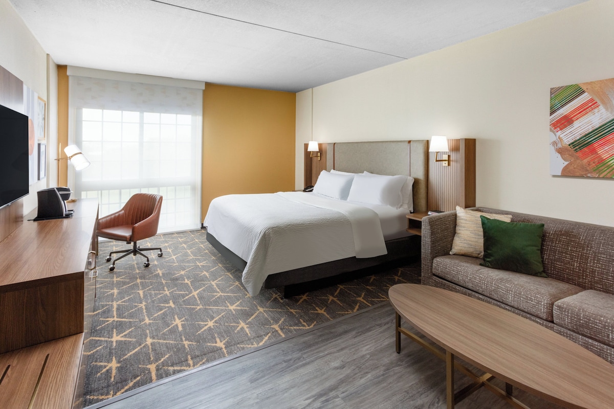 Une chambre d’hôtel équipée d’un lit, d’un bureau, d’une chaise, d’un canapé et d’une télévision.