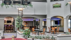 A spacious lobby with multiple seating areas, a bar, and a sign indicating a lounge area.