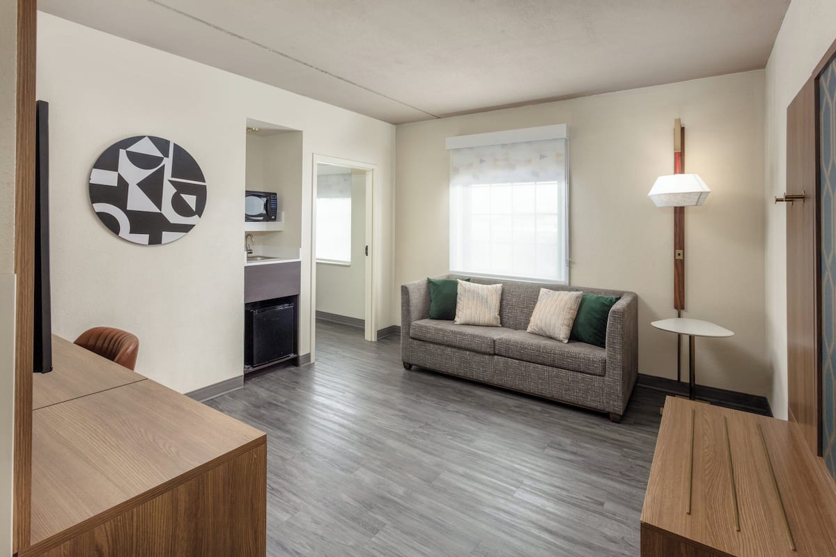 A modern living room with a grey sofa, wooden coffee table, and a wall-mounted abstract art piece.