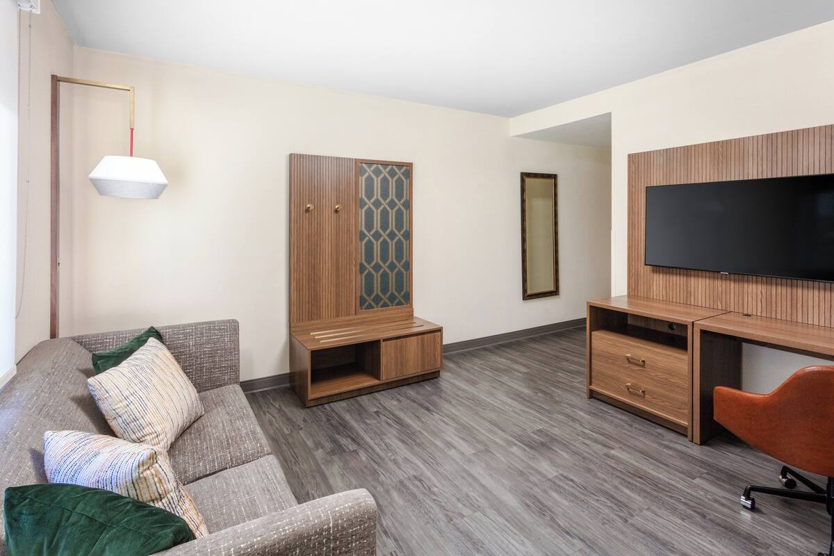 A modern living room with a sofa, a TV, a wooden cabinet, and a mirror.