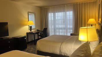 Habitación de hotel con dos camas, un escritorio, una silla, un televisor y dos lámparas.