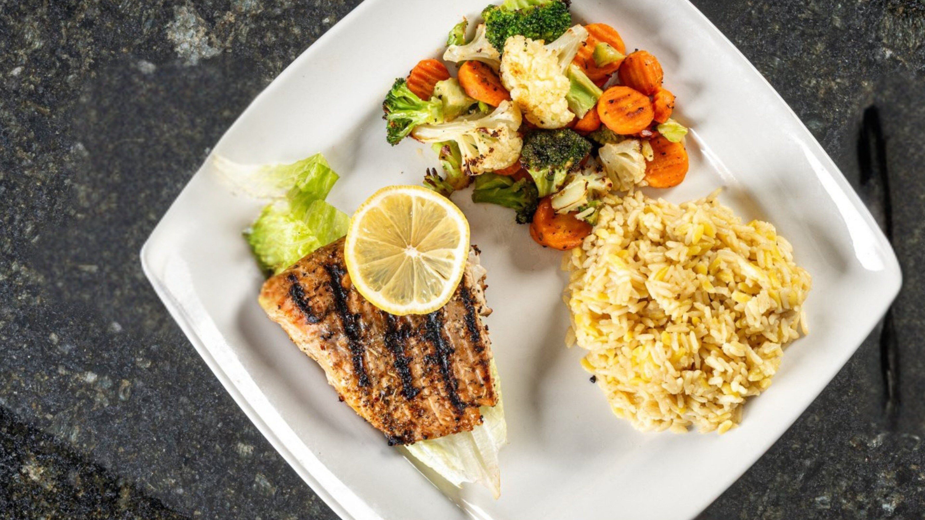 Un plato con pollo a la parrilla, verduras al vapor y arroz.