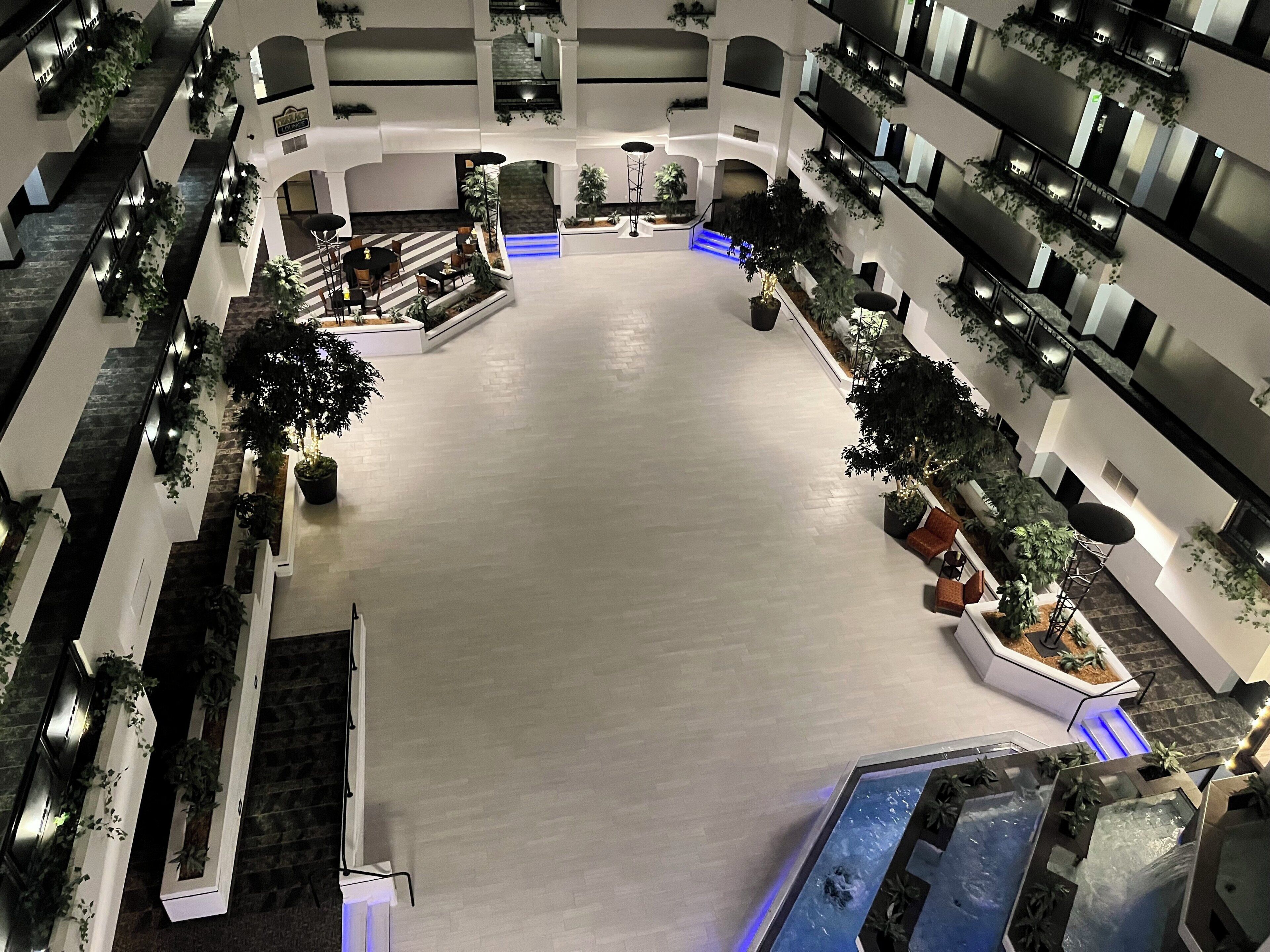 Ein mehrgeschossiges Atrium mit einem zentralen Innenhof, mehreren Sitzbereichen und Zimmerpflanzen.