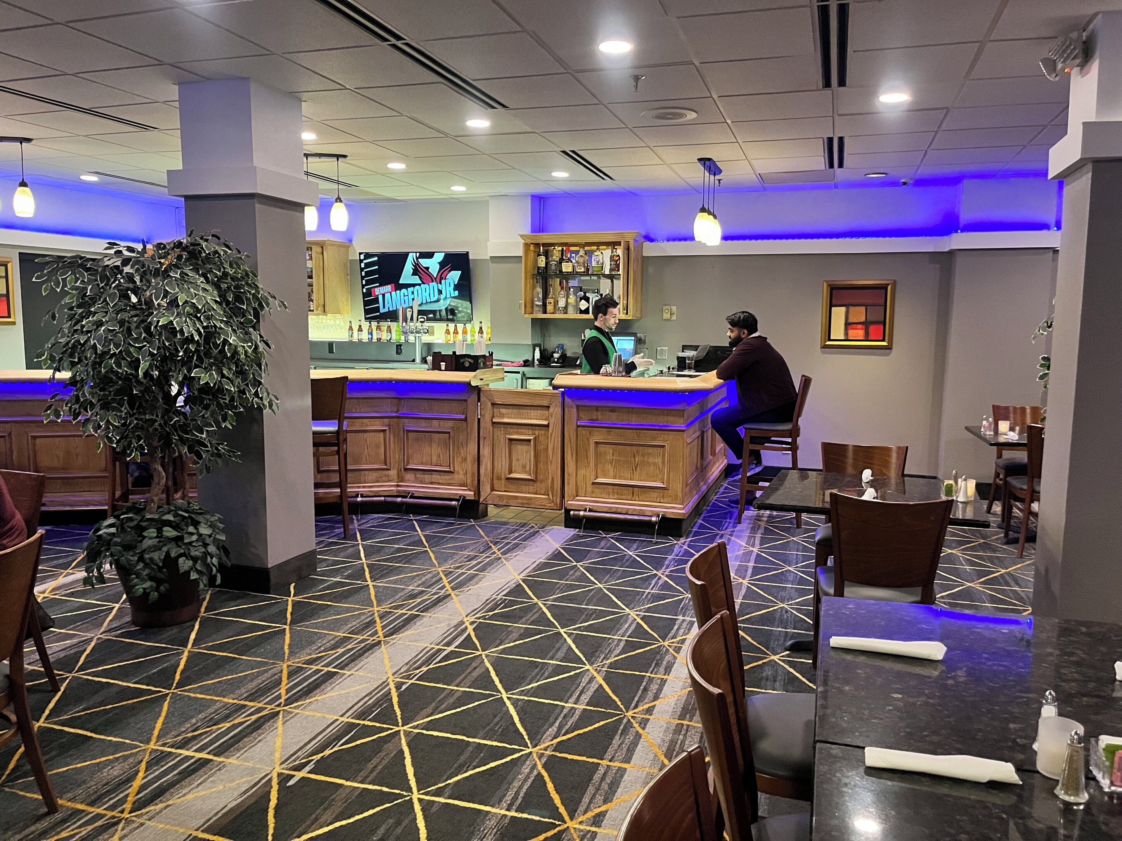 Zona de bar con mostrador, asientos y una pantalla de televisión.