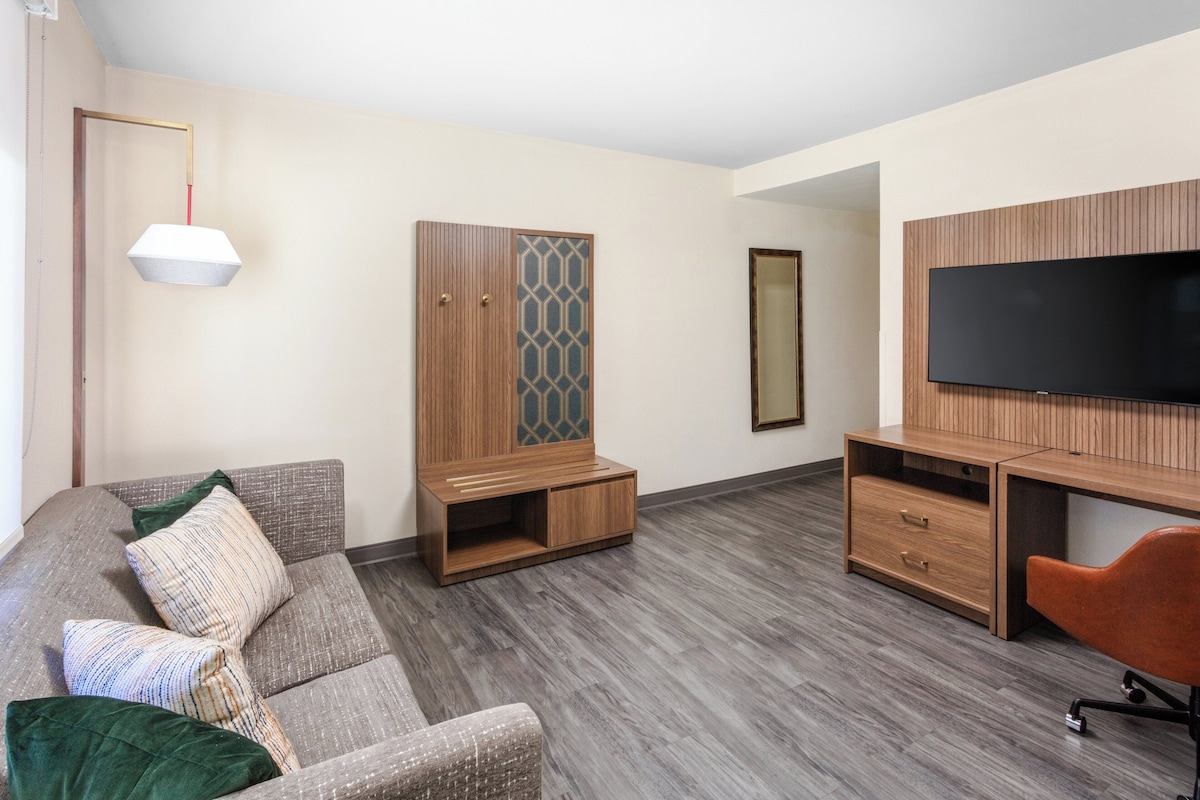 Un salon moderne avec un canapé, un téléviseur, un meuble en bois et un miroir.