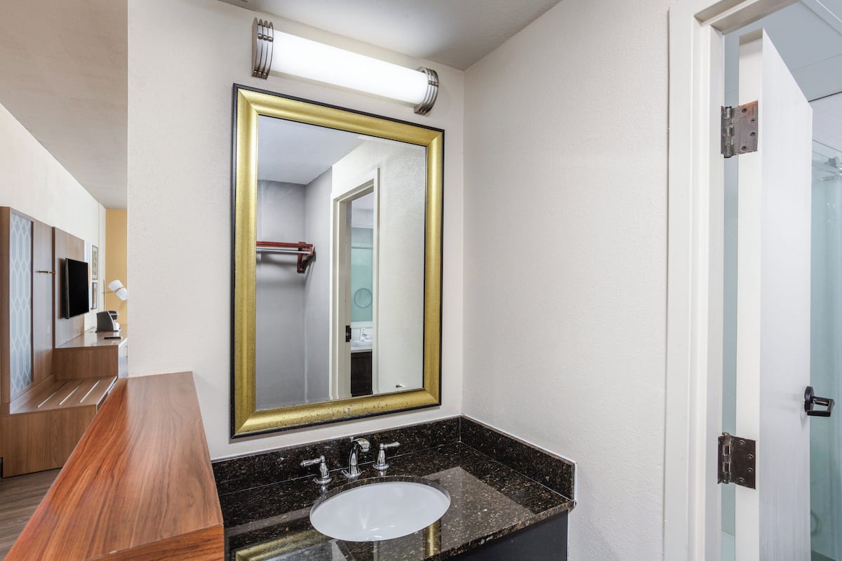 A bathroom with a large mirror, a sink, and a wooden vanity.