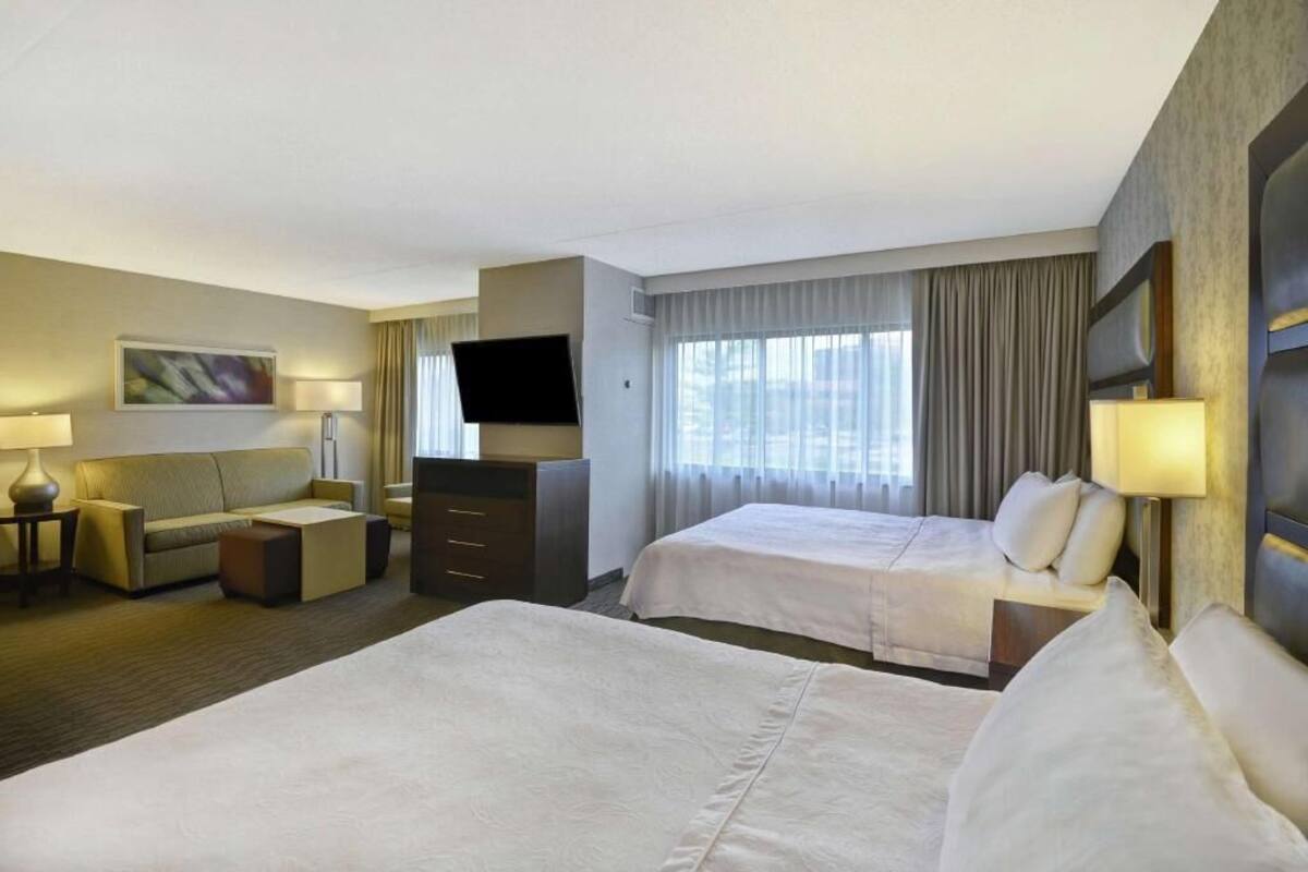 Een hotelkamer met twee bedden, een bank, een televisie en een bureau.