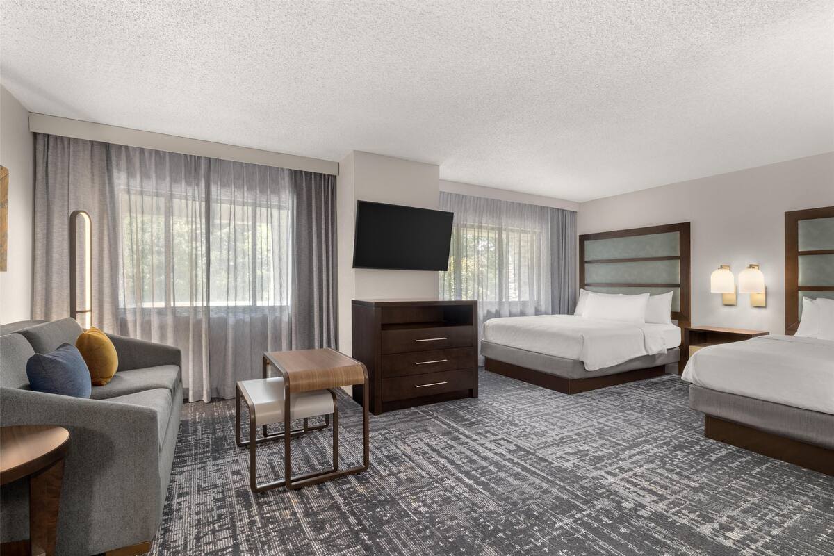 Een hotelkamer met een bank, een klein tafeltje, een bed, een dressoir en een televisie.
