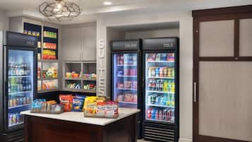 A room with two large cold storage units, a central counter with snacks, and a ceiling light fixture.