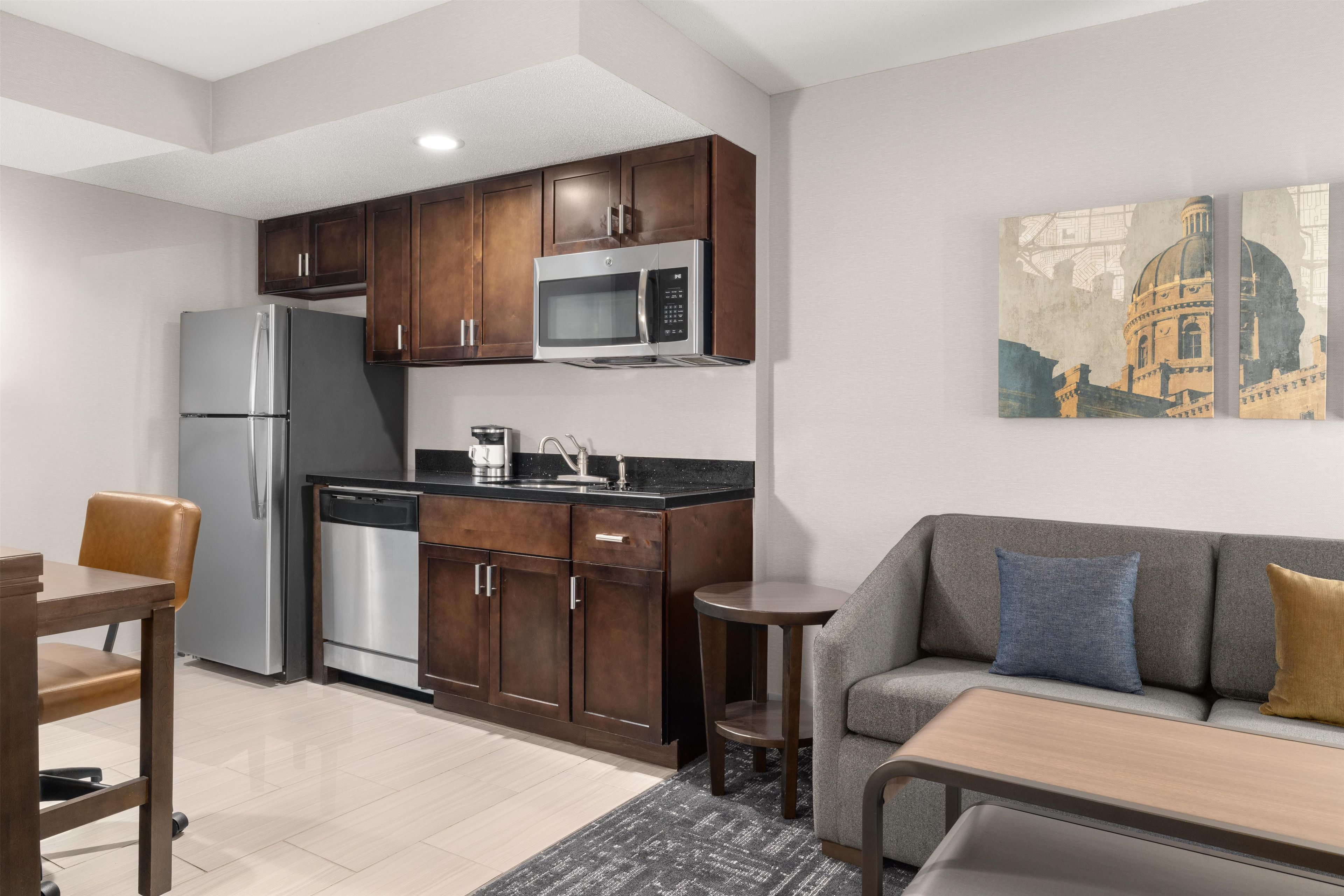 A modern kitchen with dark wood cabinets, stainless steel appliances, and a dining area with a sofa and table.