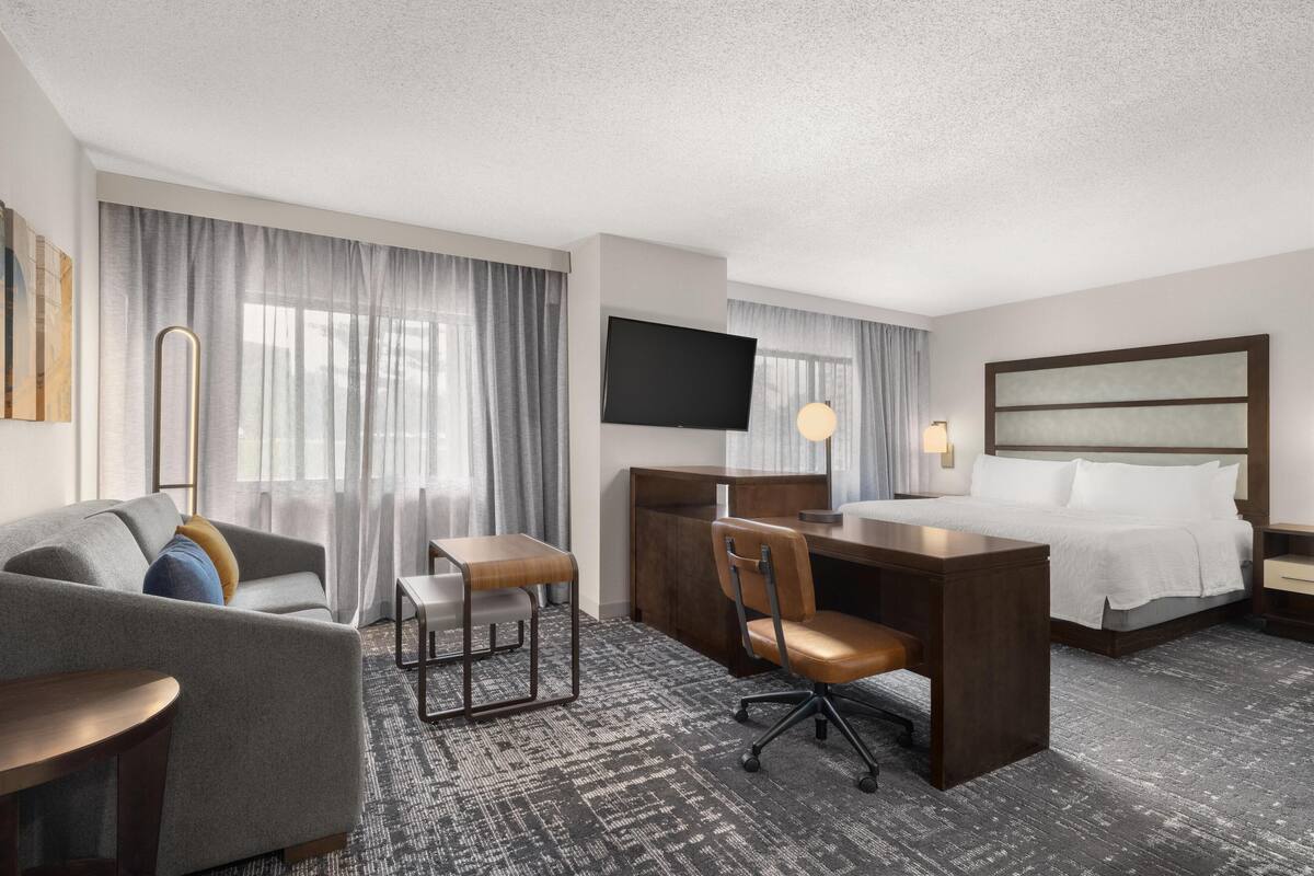 Een hotelkamer met een bed, een bureau, een stoel, een bank en een televisie.