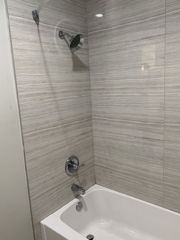 Un baño moderno con una bañera blanca, un cabezal de ducha de mano y un grifo empotrado.